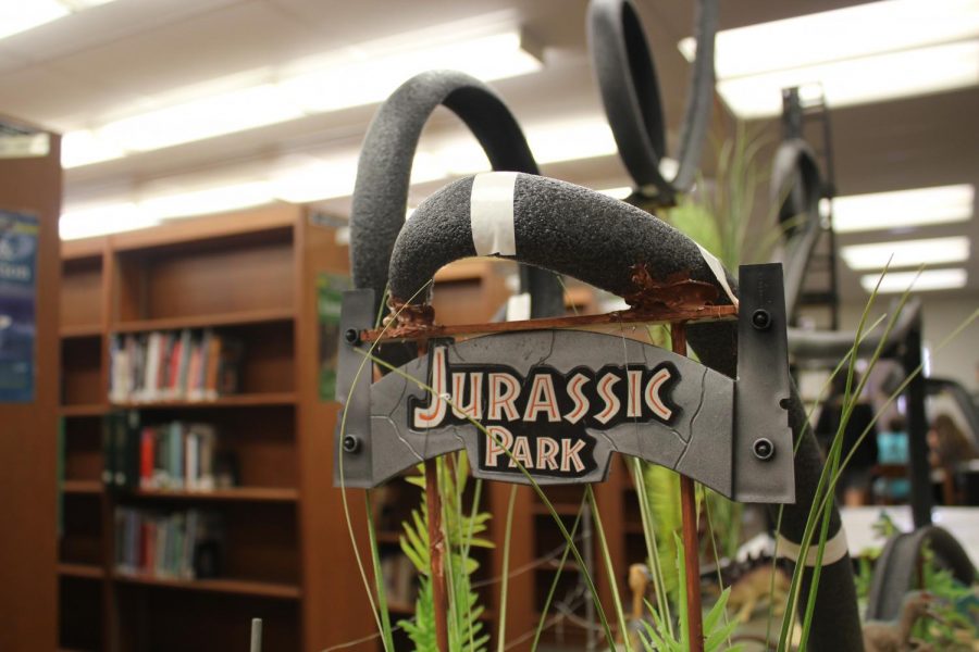 The Jurassic Park sign hangs from the track of an academic physics roller coaster in the library. The coaster had many loops, curves, and inclines included, as students were graded on the features of their coaster.