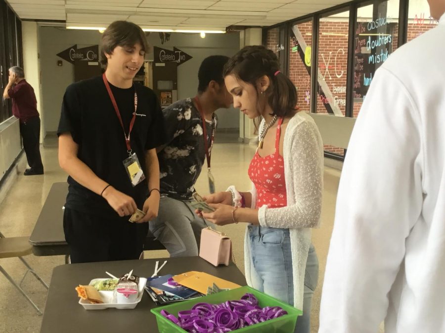 Buy one! Junior Mychenze Alberts sold the #BeLikeChuck bracelets on the bridge to a fellow student.  Students bought the bracelets during their respected lunch periods. 