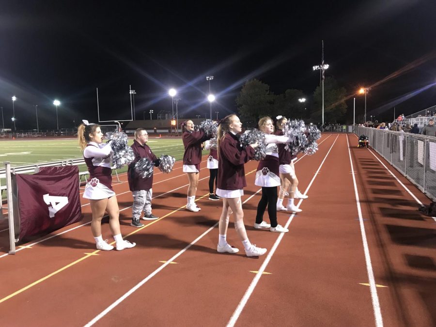 Vallei, pictured on the left, cheers with Sparkle Cheer during halftime at a football game. Sparkle is an all-inclusive cheer squad that Vallei participates in as well. 