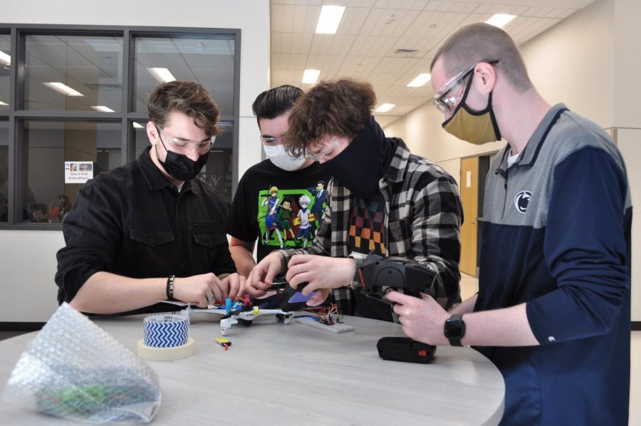 (Left to right) Seniors Derek Sisito, Kaelab Ruggles, Ethan Pacifico and Corey Aikens build their robot during the competition. This team was one of two air teams from the class and placed first in the competition. 