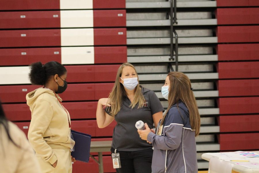 Masking Up Physical education teachers Julie Schmoke and Megan Yingling talk with a student during the first day of school activity fair.  Masks were optional for students at the start of the school year but are now mandatory unless a mask exemption is submitted to administration.