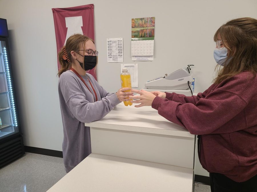 Snack time 
Senior Abigail Quinn hands senior Madison Zimmerer a drink during her community service period. Many students stopped by the school store to get snacks for the day.