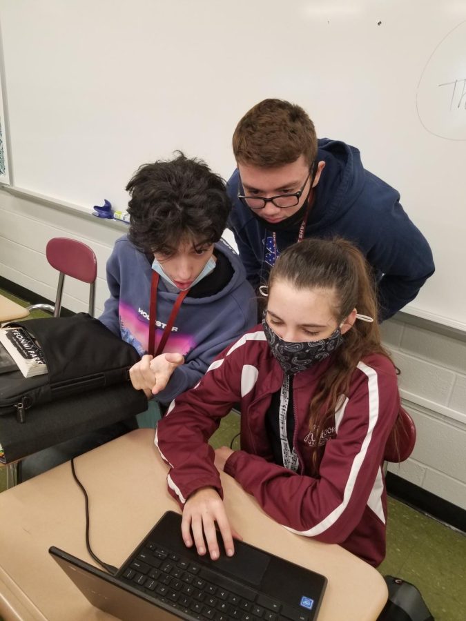 Workin’ together. Juniors Ethan Dennis (left), Julia McCauley (right) and Owen Smithmyer (middle) work on their English work together. The students worked throughout sixth period making sure their work was perfect for the teacher. 