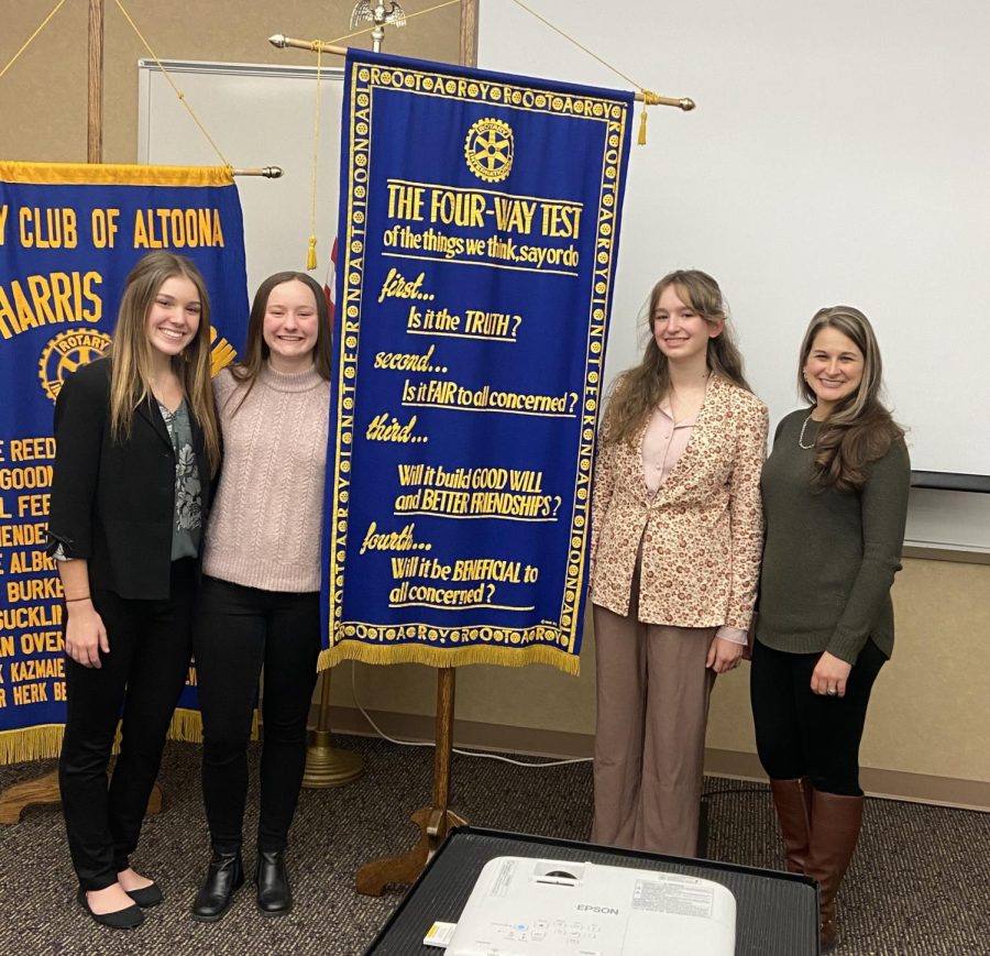 Congrats. Senior Danielle Mueller,  senior Abby Smearman, sophomore Ava Rokosky and adviser Heather Tippett-Wertz pose for a picture in front of the 4-way test banner. Smearman placed first, Mueller placed second, and Rokosky placed third. Each received a cash prize for their achievements. 