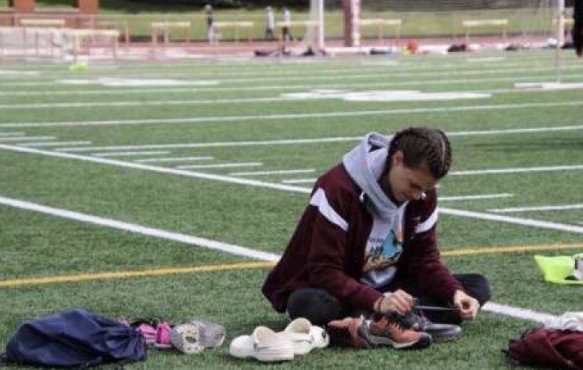 Gearing up. Junior Gwyneth Fox is untying her shoelaces so she can put her shoes on for her track meet. 