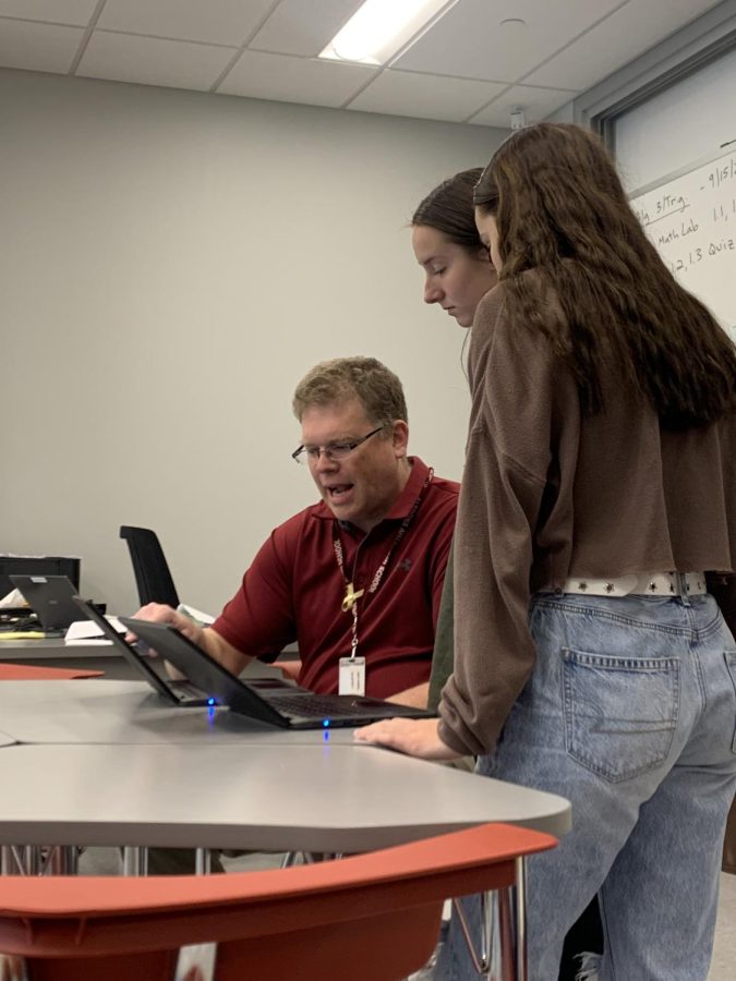 Tutor time Math teacher Joseph Falger shows juniors Olivia Confer and Laney Yost how to complete the equation correctly on their Chromebooks. Exposure to technology such as this is what is detrimental to students learning.  