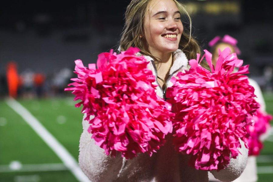 Smile! Bailey Gerlach cheering at the breast cancer awareness game, showing her support by using the pink pom-poms. She smiled through the whole game to show she is there to support and cheer. 