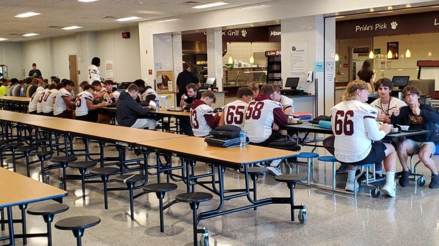 The football team sits down to indulge in breakfast together before an away game. 