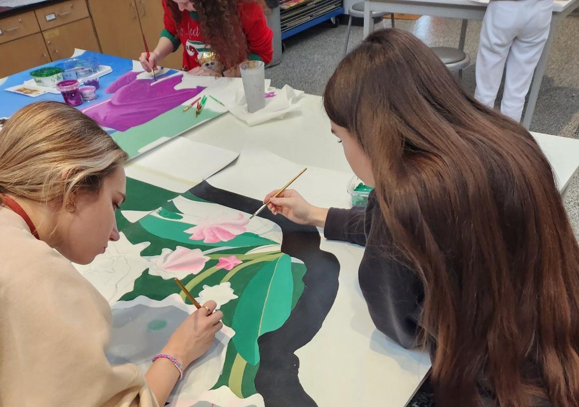 Time to paint Sophomore Haley Tanzi and junior Aleah Layton paint pieces of the mural. Tanzi and Layton worked on the mural front start to finish as part of the Art in Public Spaces class.