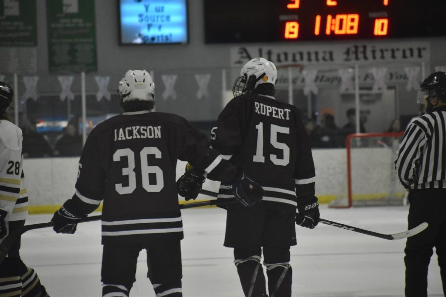 Standing together. Senior Liam Jackson and Junior Garrett Rupert skate down the rink in between periods. 