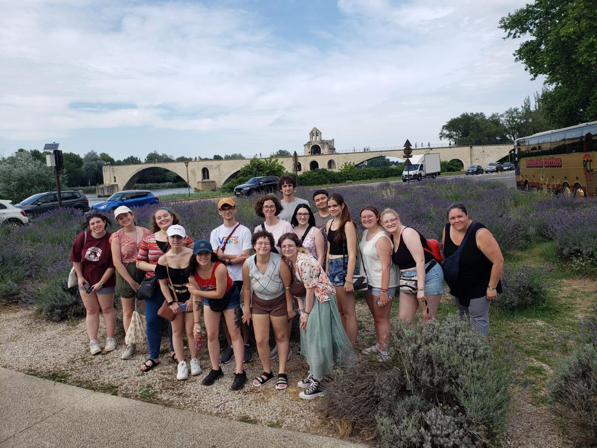 Crossing  a bridge. Students pose for a picture in front of the Avignon Bridge with a lavender field behind them. 