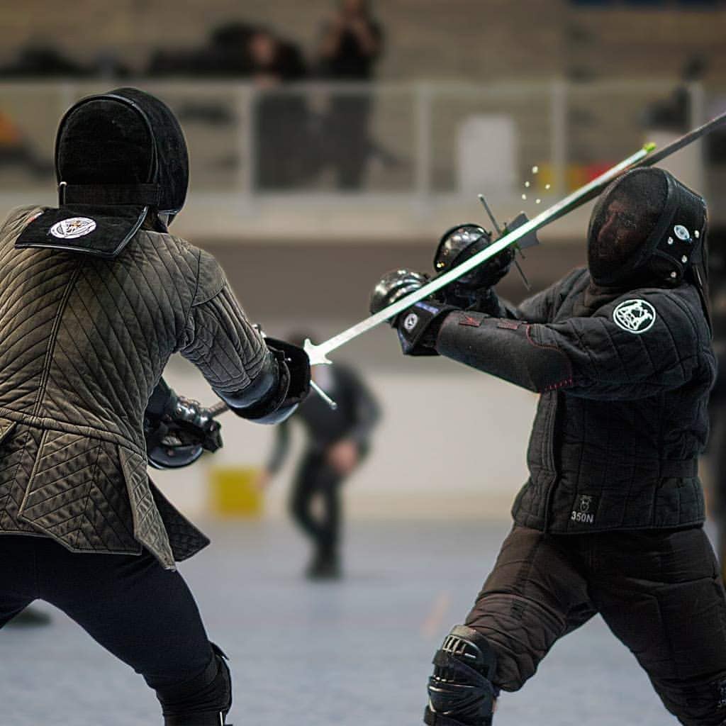 En garde. Greatsword fencing is one of the only disciplines that requires a two-handed grip. The most common armor is a tunic and face guard. 