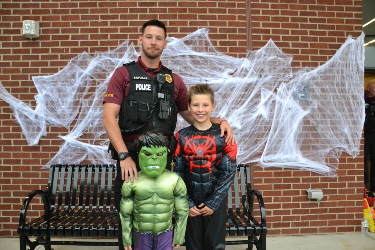 Halloween heros. Officer John Mcfalls poses with his sons for a photo during the 2022 trunk or treat. His kids enjoyed showing off their costumes to the other staff members