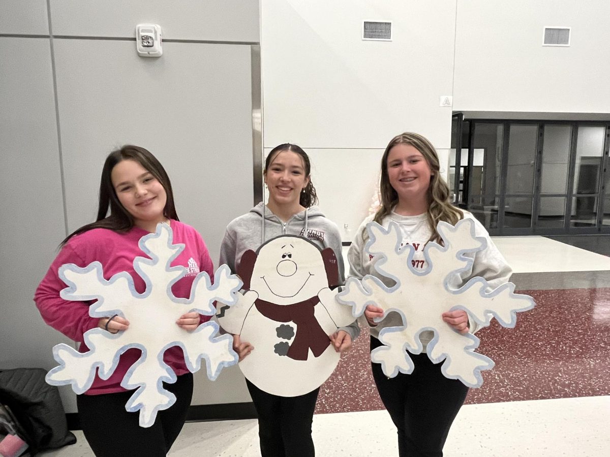 Merry Christmas. Sophomore Rylee Bush and freshmen Elexis Hawksworth and Lilly Stahlman pose with their snowflakes and snowman before practice. The three will take part in the downtown Altoona Christmas parade.