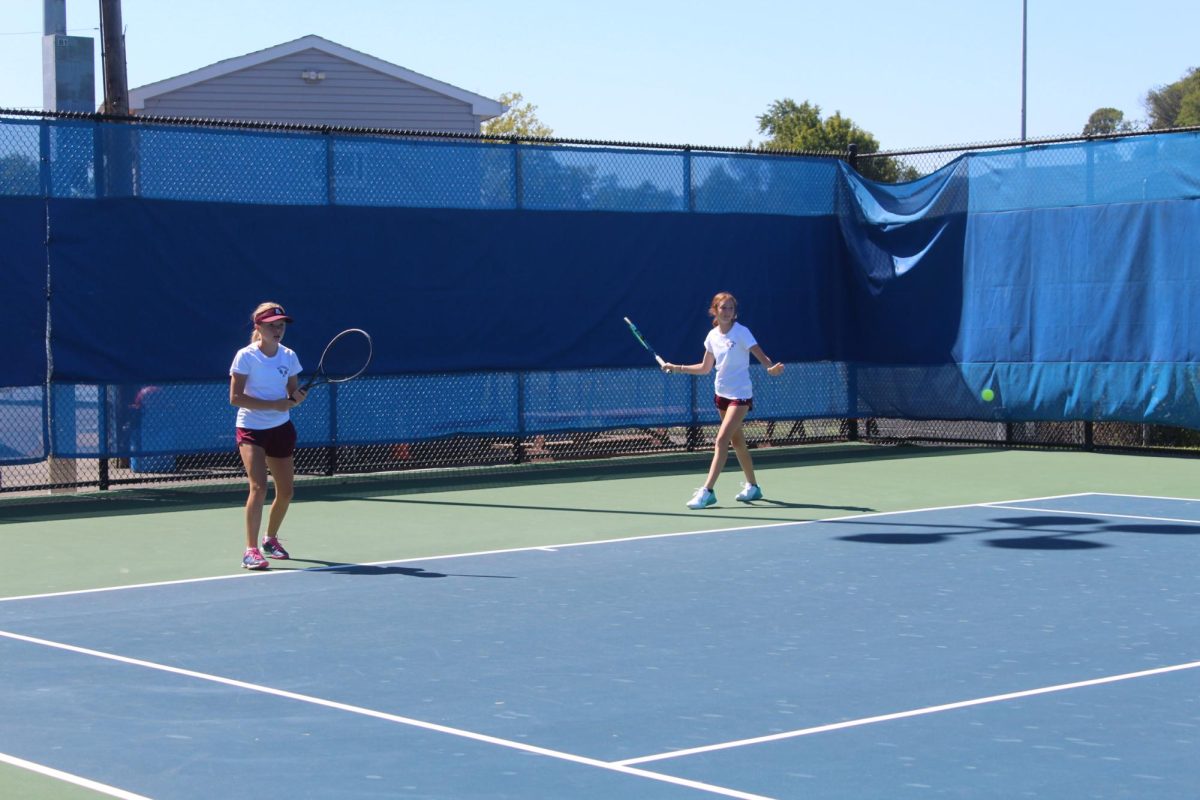 Warming up Freshmen Evelyn Adams and Skyler Irwin stand at the baseline to warmup before their tennis match. Later in the season, Irwin suffered a knee injury which took her out of the lineup for the rest of the season.