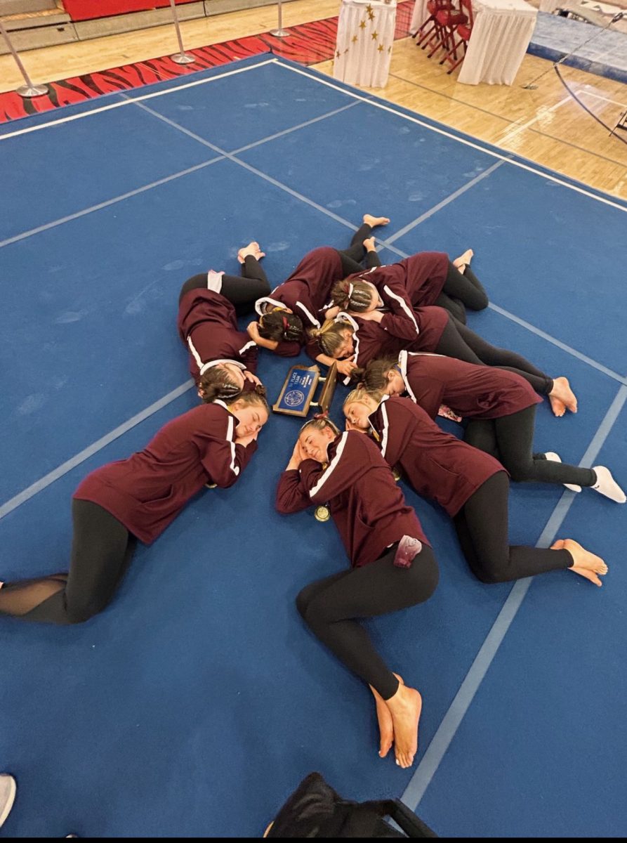 Sleepin on the victory. The gymnastics team poses for a sleepy photo with their award. 