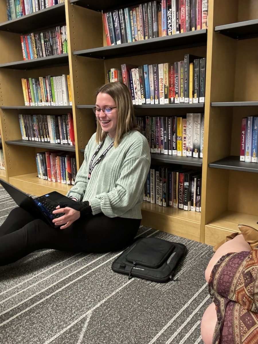 Smiling wide. Senior Jaidyn Palladini enjoys talking with friends while getting work done for Mountain Echo. 
