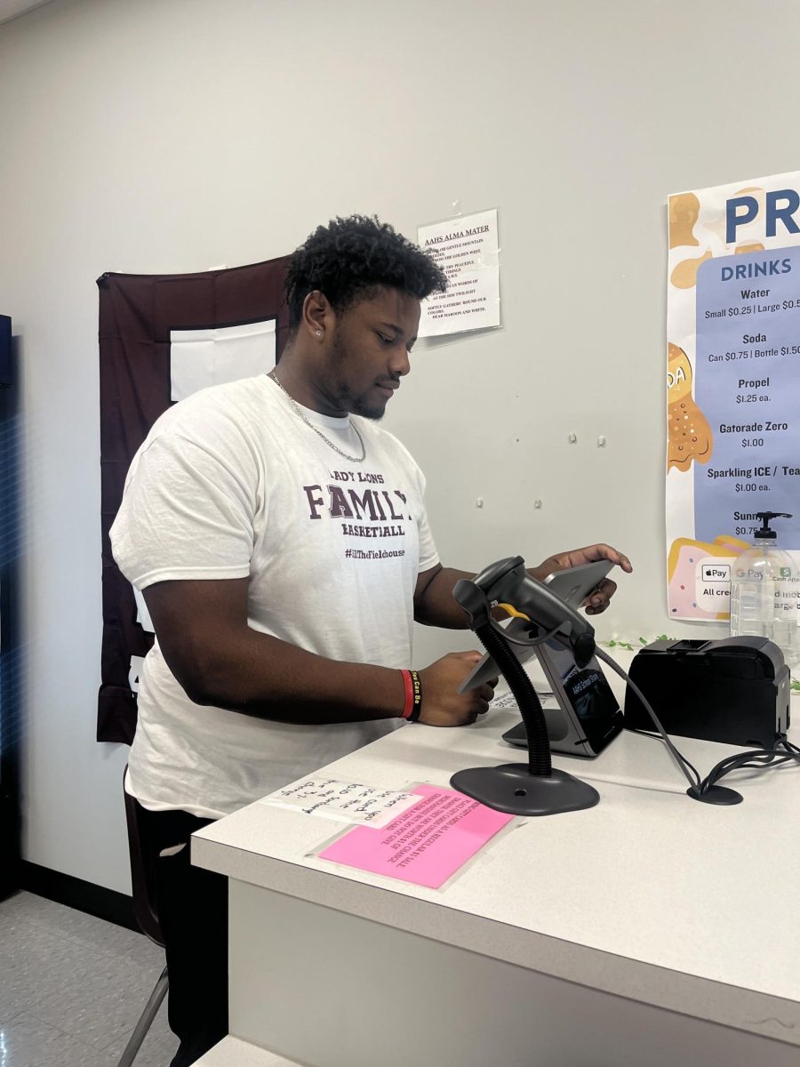 Locked in. Senior Derron Jones works the school store during seventh period. Jones is responsible for stocking the store and working the register. 