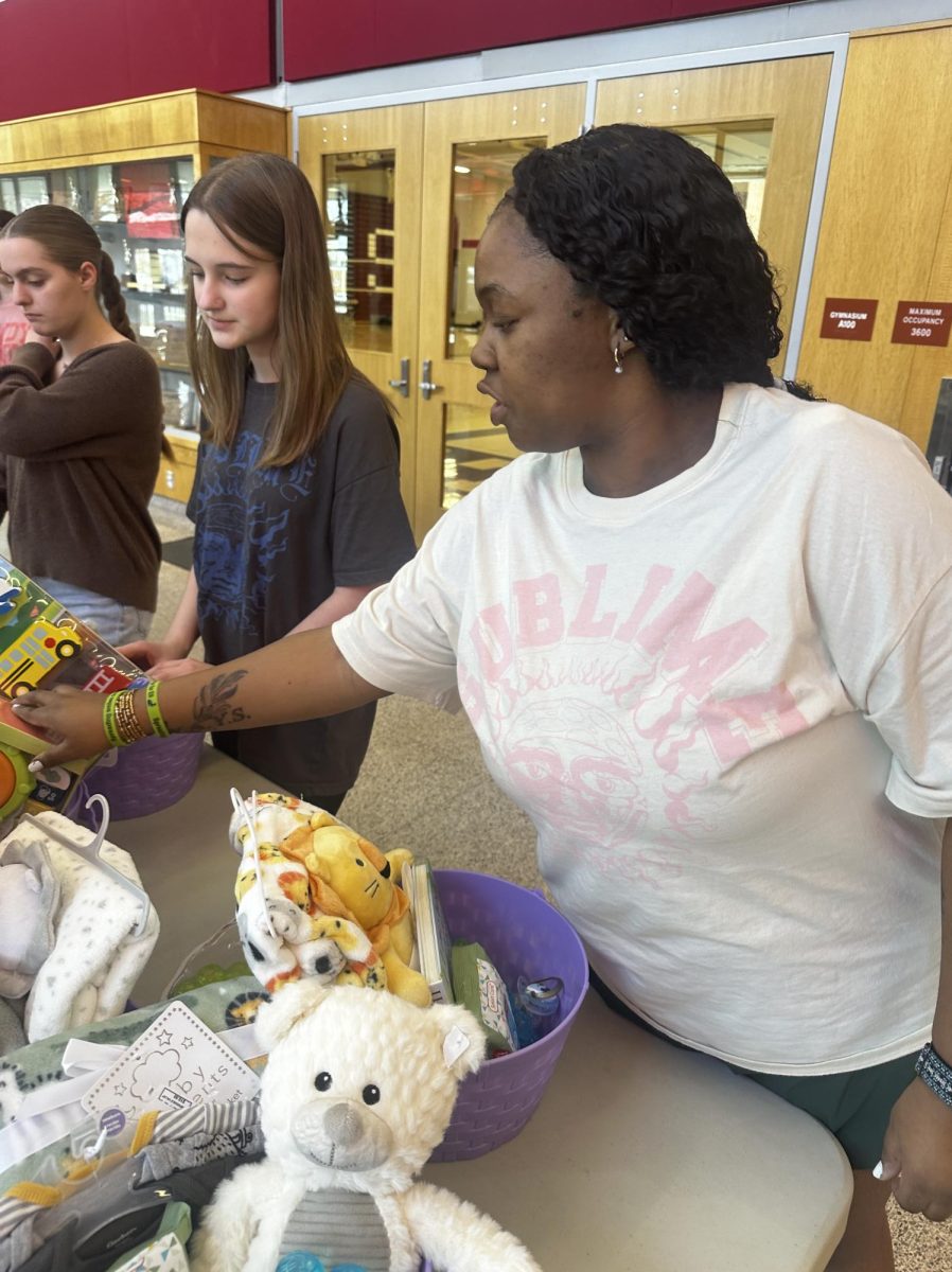 Helping hands. Senior Aaliyah McGee helps junior Giada Lattieri pack her Easter basket. The girls all work together to make the process easier.