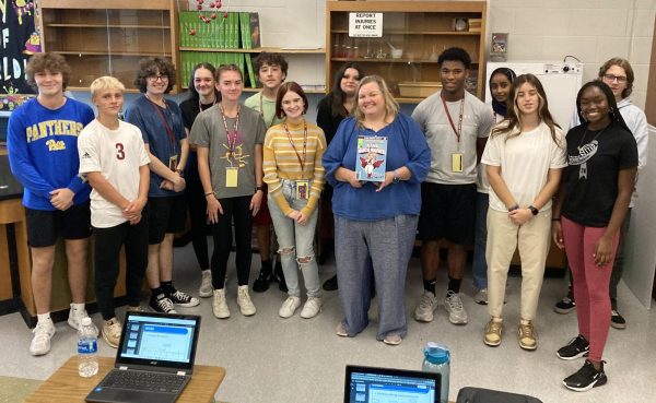 Chemistry Champion. Chemistry teacher Christine Falger was designated a comic book superhero during the 2023-2024 school year. She poses with her seventh period honors chemistry class, accepting the award. This is a result of the Climate and Culture squads work around the school, which focuses on building teacher morale.  [Being part of a squad] is a big time commitment. We as a squad are required to give one hour of time a month, I am probably anywhere from eight to 12 hours a month, Krug said. [But the squads work] can make the high school a better place. I am really lucky to work with a number of teachers who also feel the same way. Even if we are doing more than some squads at the high school, we still feel like what were doing is really important. (Courtesy of James Krug)