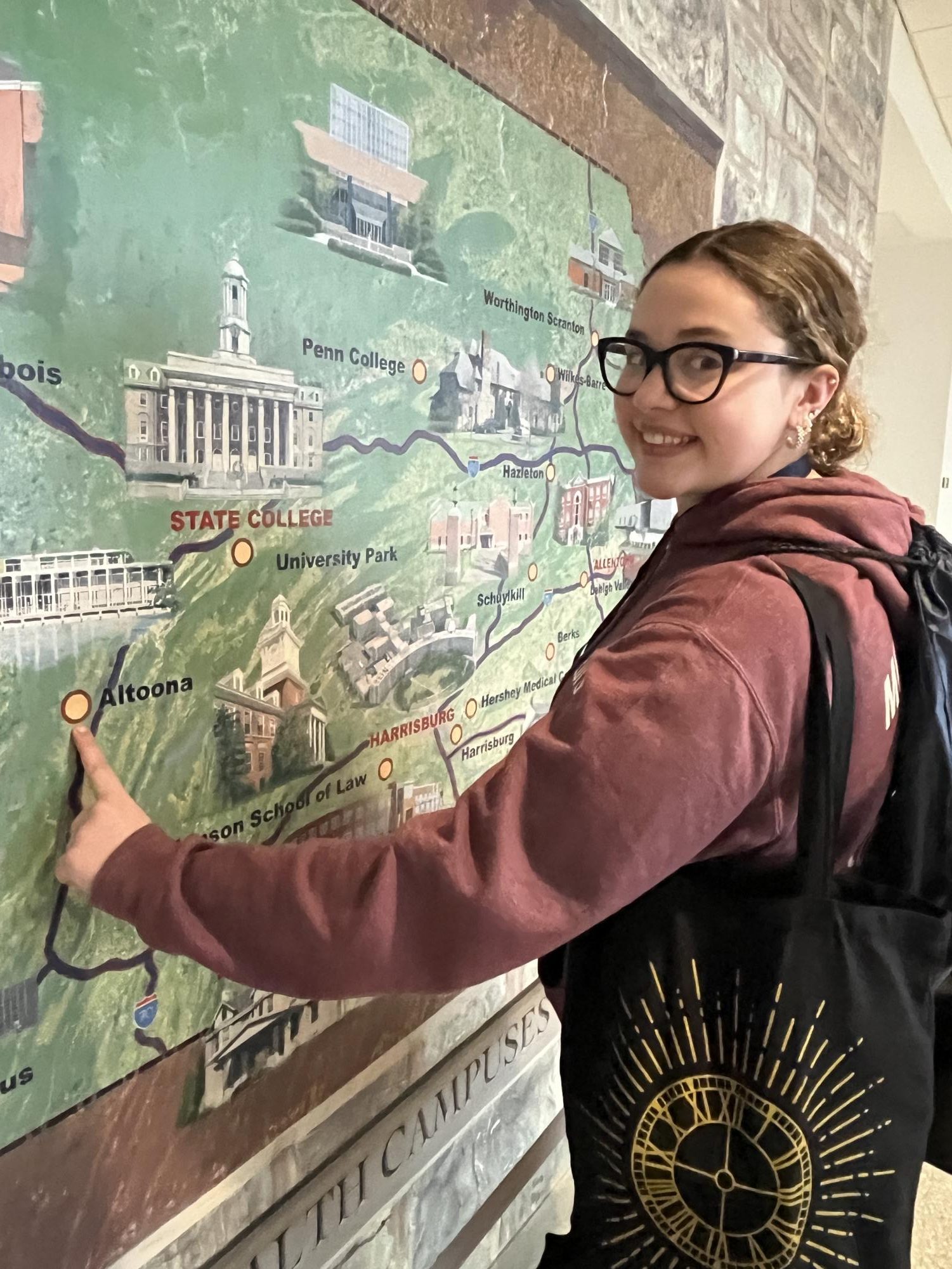 Our Turf. Associate editor Charlie Kephart poses with one of the various maps around the Hub on the Penn State campus. While State College is only a 45 minute drive from Altoona, Charlie wished she could go back more often to Penn State. 