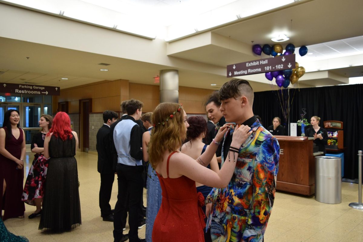 Touching up.  Two students gather near the snack stand as they get a break. She repositions his bowtie before returning to dance.