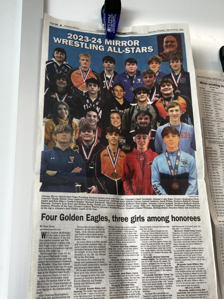 Take down, Gilbert has a newspaper hung in his room showcasing 2023-24 Altoona Mirror wrestling all-stars. There are three girls who appear in this photo, showing girls can wrestle too. 