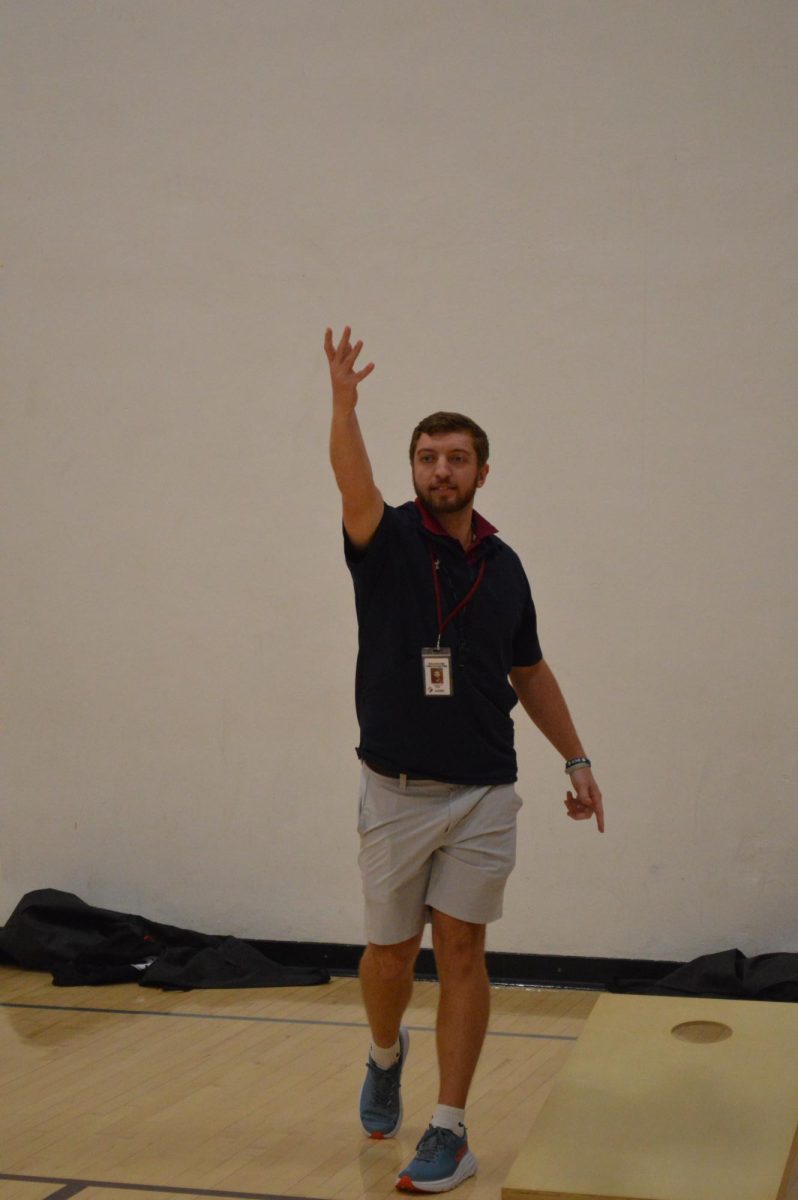 Brandon Lingenfelter shows his fifth period class the rules of cornhole. Lingenfelter tossed the bag and it landed ion the board, earning one point. 