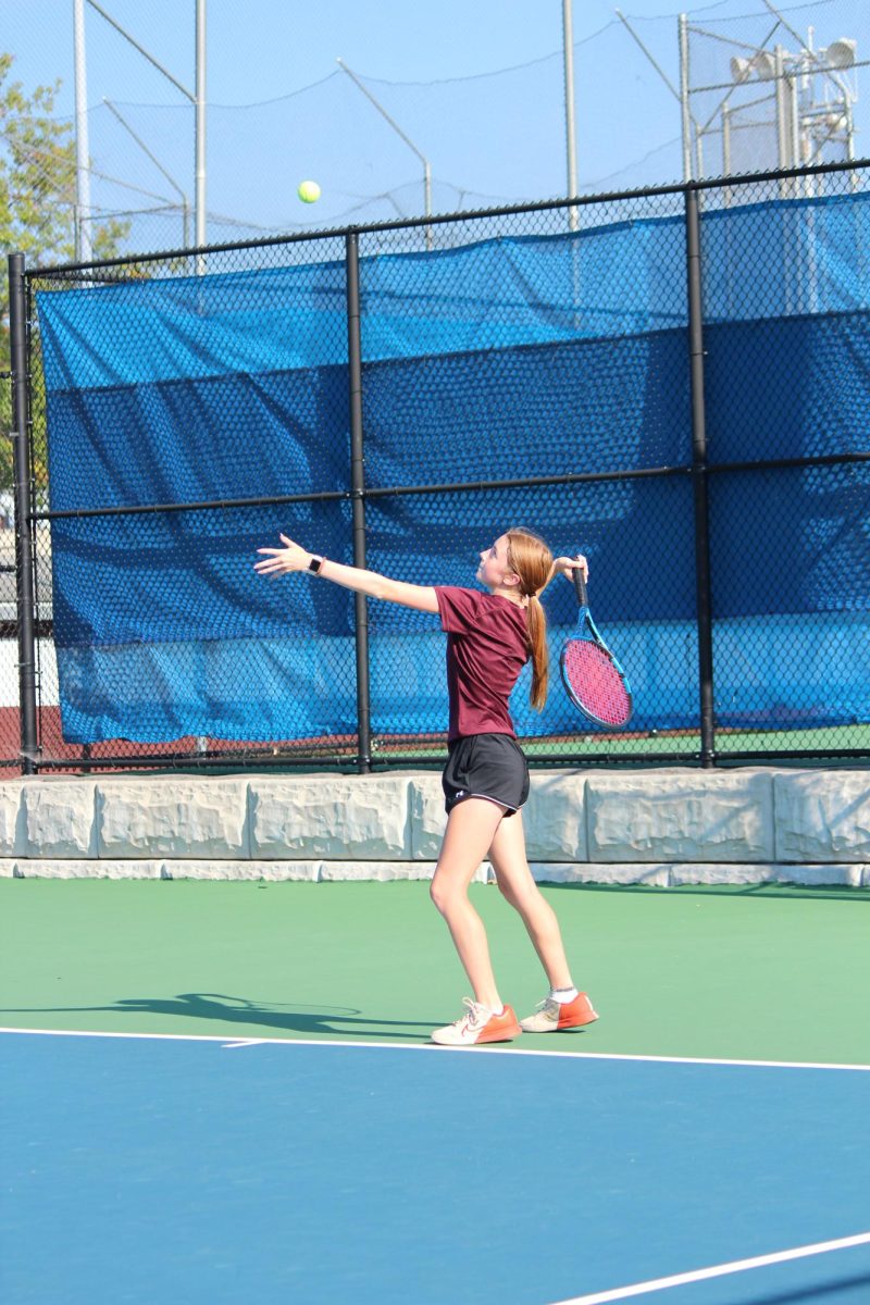 Senior Courtney Iwin throws a tennis ball, preparing to serve. C. Iwrin has played tennis for multiple years. 