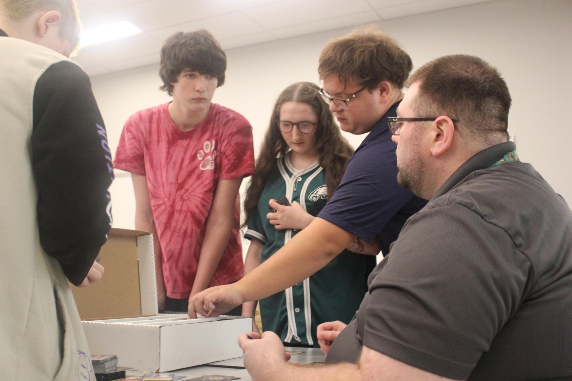 Daniel Harber teaches James Evans, Tiffanie Evans, Matthew Diehl and Archer Makarikas about a card game at the first Gaming Club meeting.