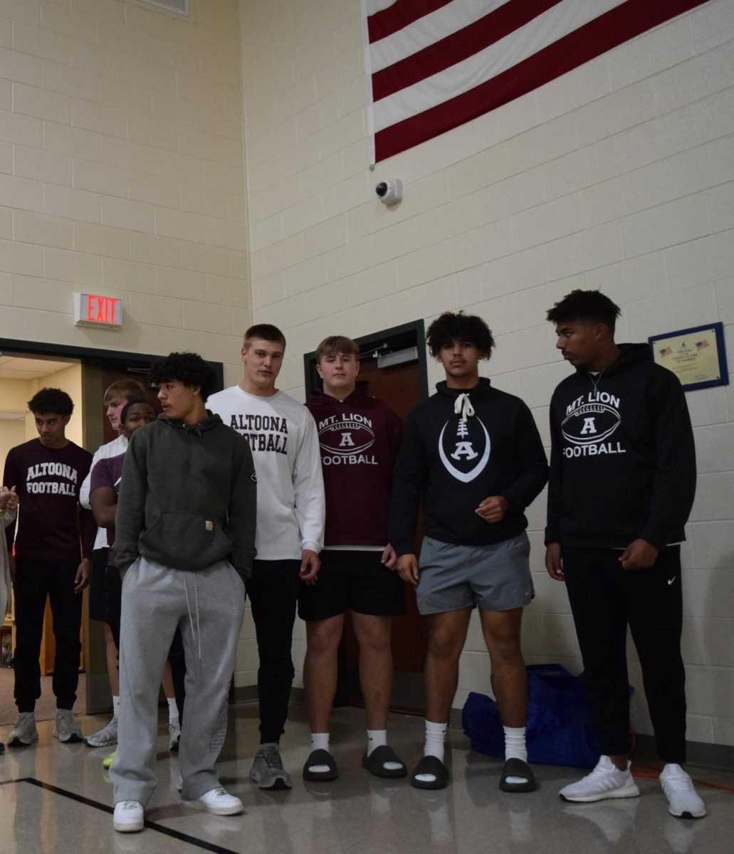 Watching closely. Jamaine Thomas, Max Chille, Mark Harrington, Branson Adams, Max Steele, Markell Herr and Amar Emeigh-Ballos look out at the students sitting on the floor. Football players and cheerleaders both took part in this event. 