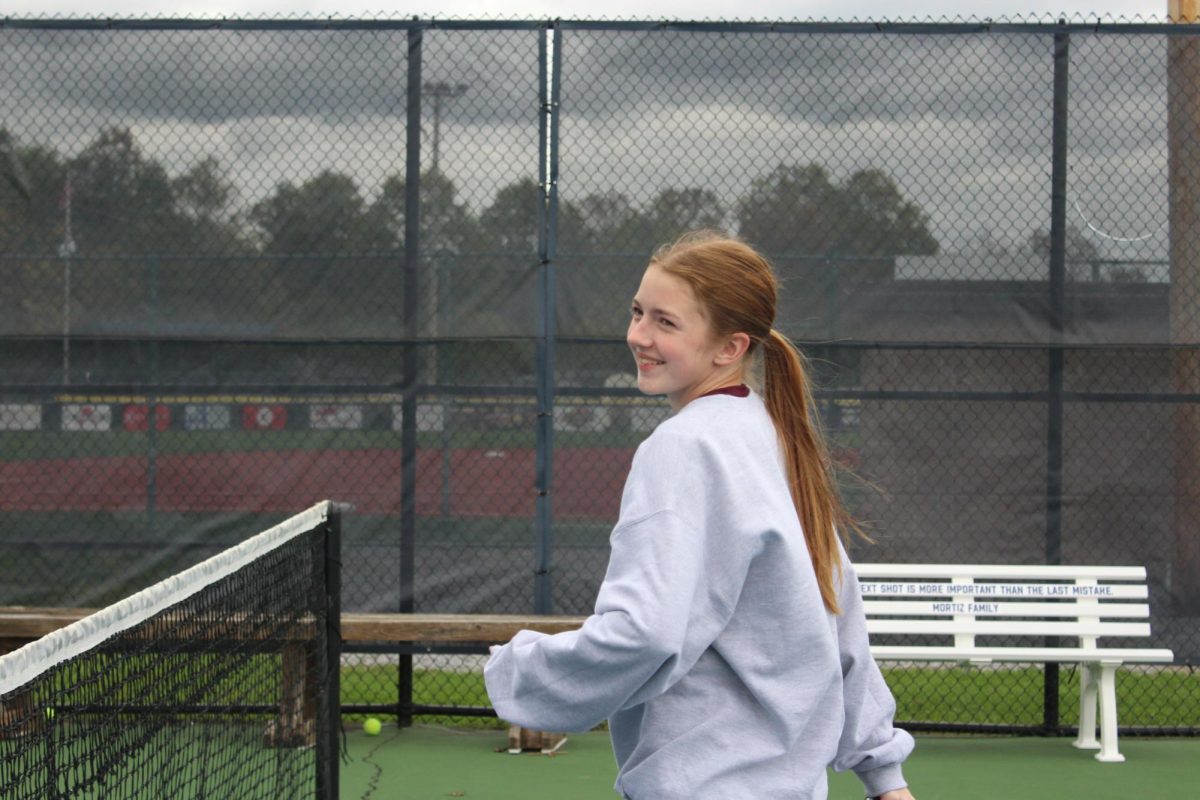 Game face. Senior Courtney Irwin is all smiles as she warms up for an important district match ahead.