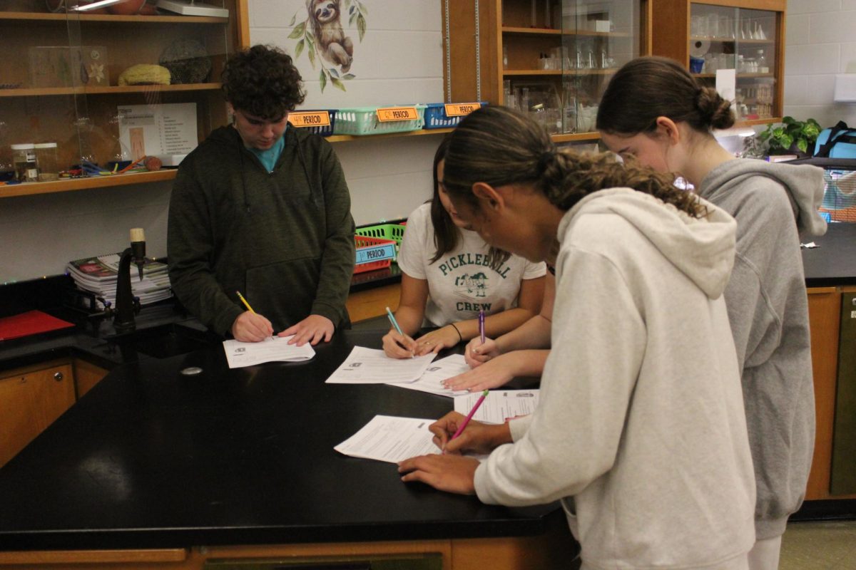 Freshmen, Addison Mitchel, Ava Williams, and Kye Walls record their collected data from their science experiment.