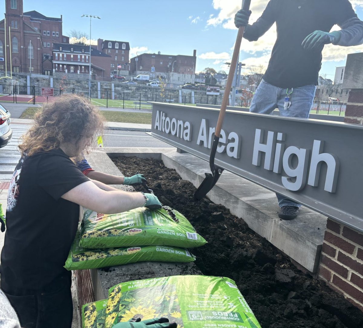 A Helping Hand. Jonah Walters opens a bag of mulch to pour over the freshly laid tulip bulbs. Walters job was to place the bulbs and lay mulch. 