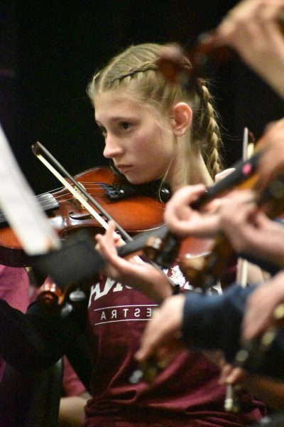 Sharing their future. Sophmore Emma Blontz reads her notes to stay in sync with everyone else, while Kelly Detwiler conducts them.