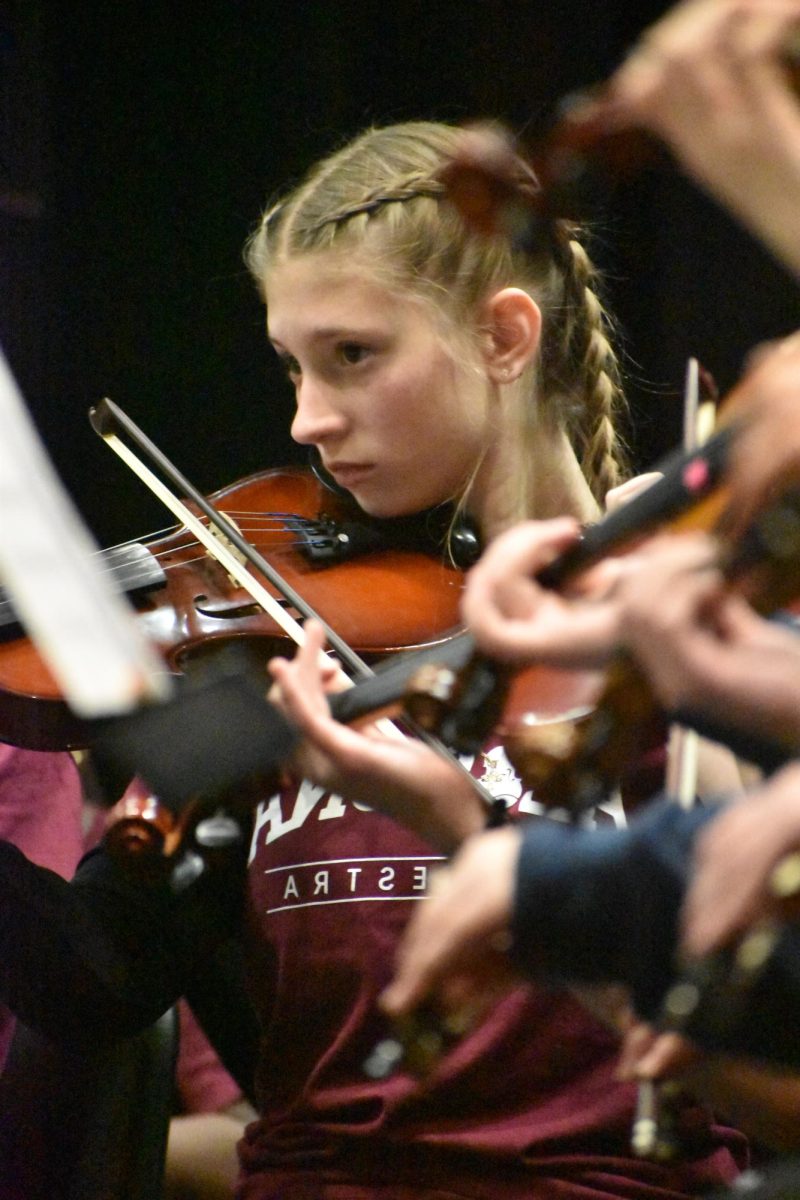 Sharing their future. Sophmore Emma Blontz reads her notes to stay in sync with everyone else, while Kelly Detwiler conducts them.