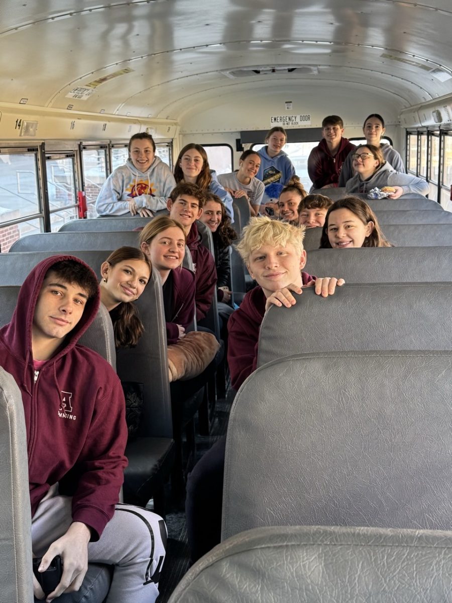 The swim team smiles on the bus after a long day of competing. 