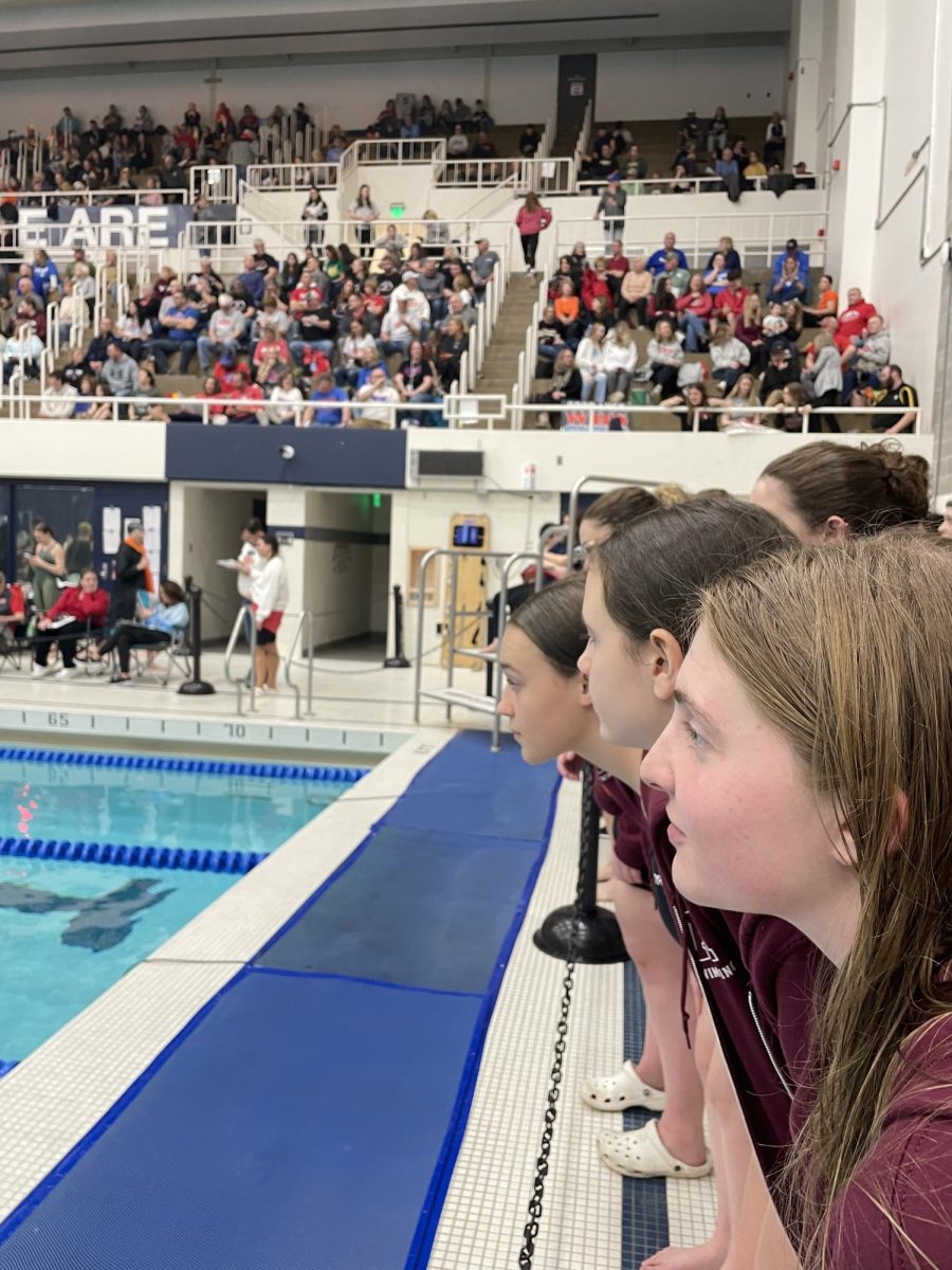 Some members of the girl's team eagerly watch their teammates compete. 