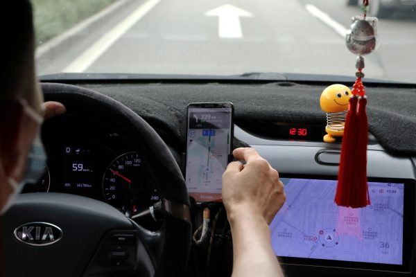 A driver of Chinese ride-hailing service Didi drives with a phone showing a navigation map on Didi's app, in Beijing, China July 5, 2021. REUTERS/Tingshu Wang