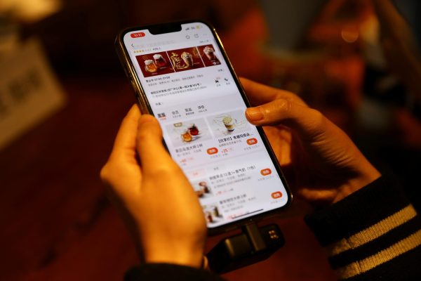 A journalist checks the Starbucks menu on the Meituan app on her phone at a Starbucks flagship store in Beijing, China January 18, 2022. REUTERS/Tingshu Wang