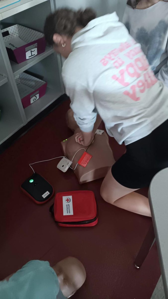 Sophomore Lainey Yoder works on her compression while the AED is telling her what beats to follow.