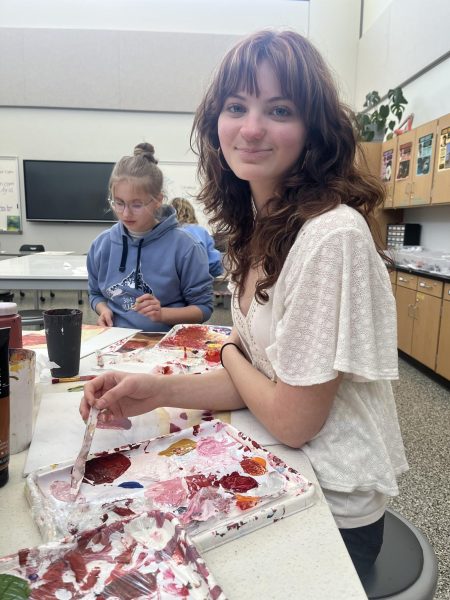 All smiles. Junior Marli Closson takes a break from painting to help her other classmates.