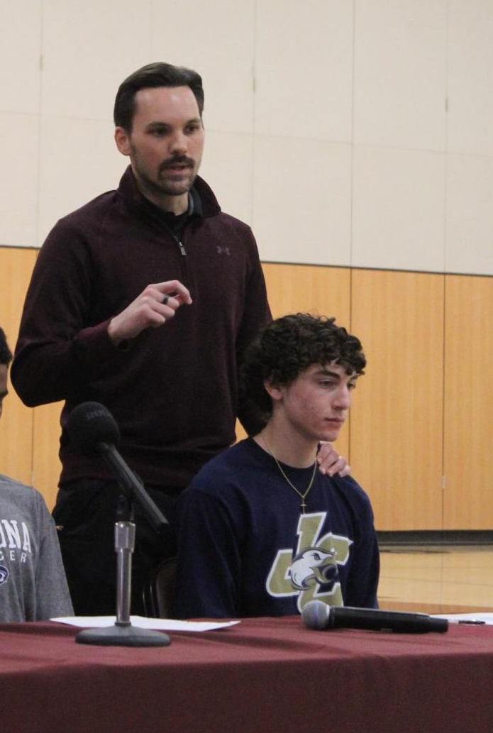 Taking the next step.  Senior Justin Bossler sits with boys’ soccer coach Travis Young on signing day.  Bossler will be attending Juniata College. 
