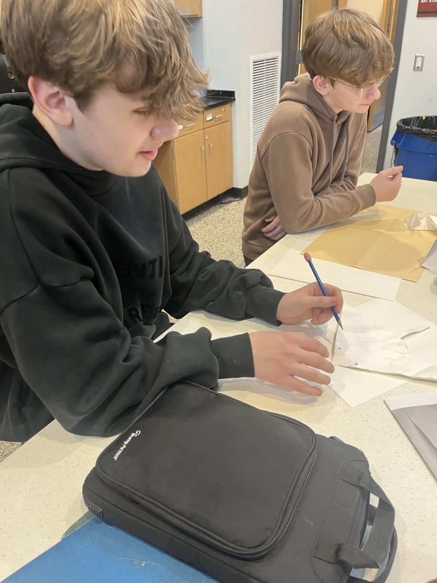 Freshmen Owen Simpson and Dylan Swanger work hard on their art project.
