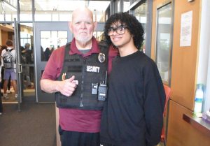 Sophmore Kevin Ortiz stands with securtiy gaurd and greeter Fred Martynuska during the moring security checks.