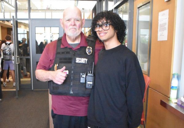 Sophmore Kevin Ortiz stands with securtiy gaurd and greeter Fred Martynuska during the moring security checks.