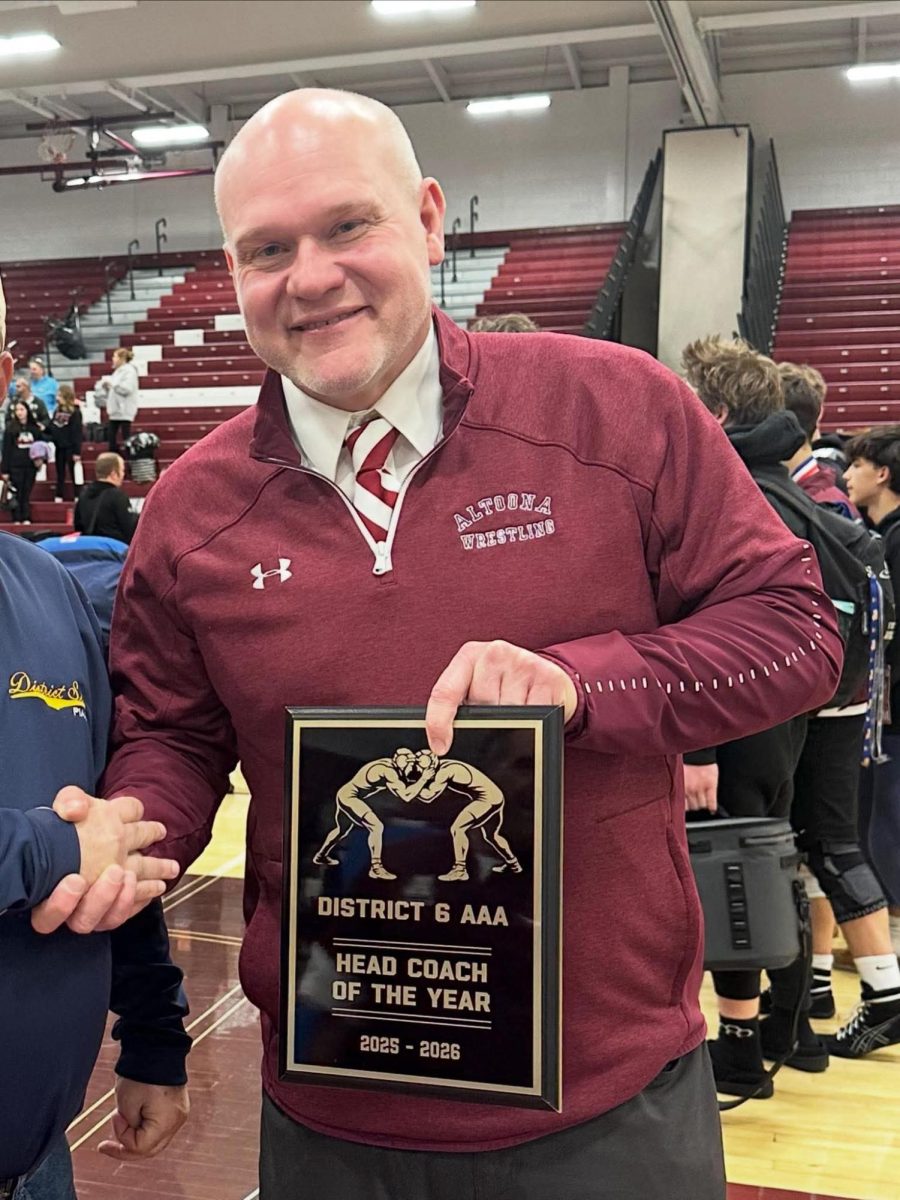 Coach Joel Gilbert holds his plaque that commemorates winning District VI Coach of the Year.