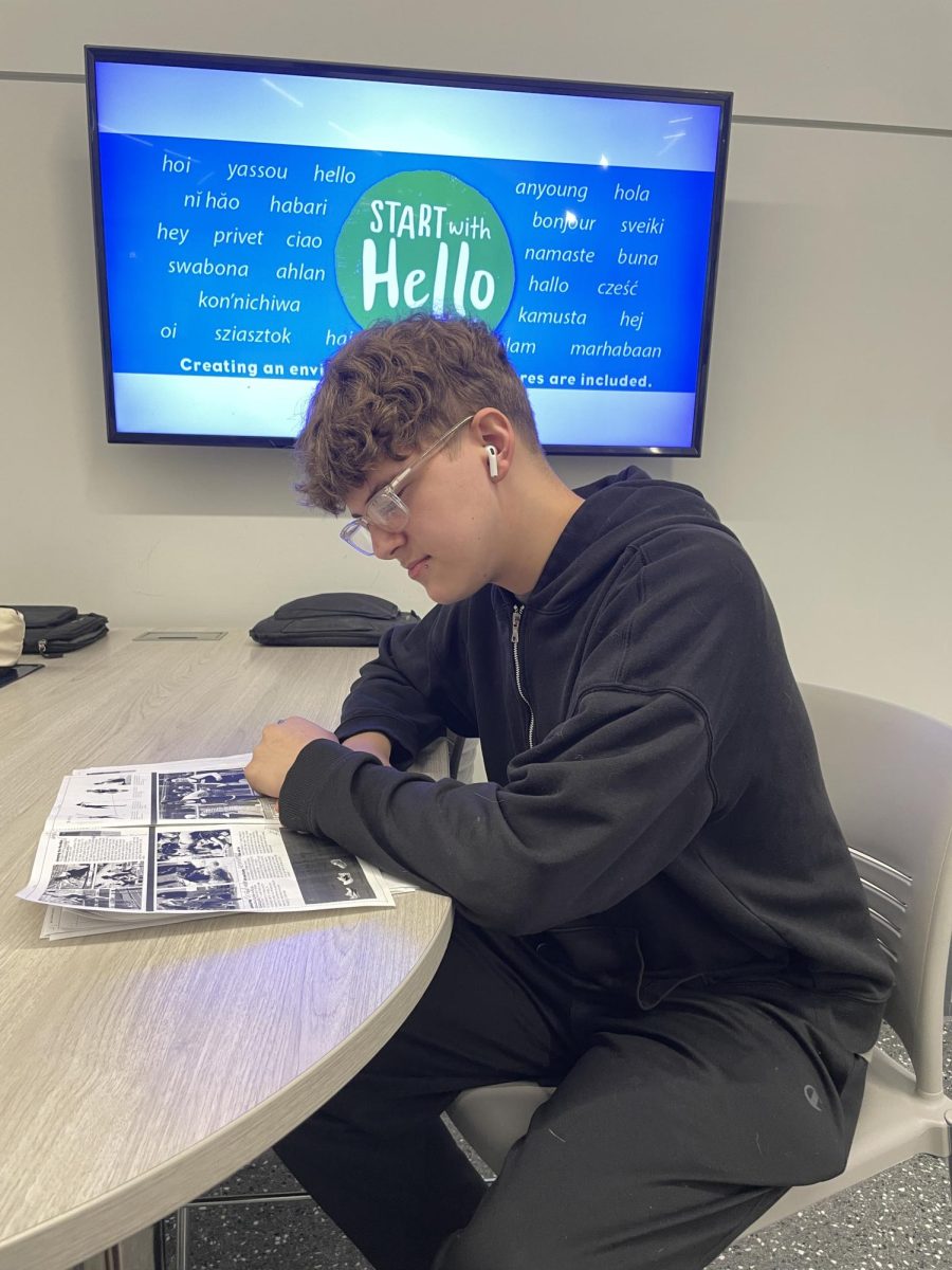 Locked in. Junior Leland Porta poses with an earbud in as he does his work. Wearing earbuds during school became a hot topic of debate among staff and students this year.
